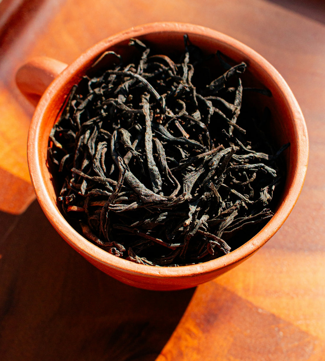 Dried black tea leaves in an orange mug