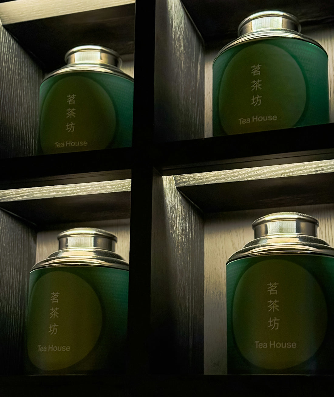 Four green tea canisters in wooden shelves