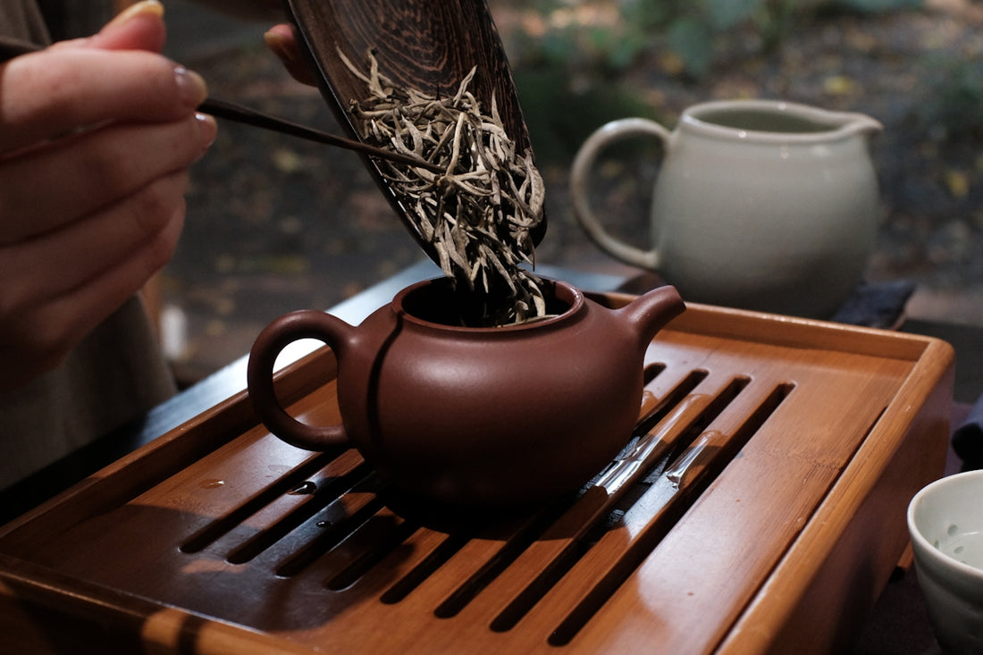Adding dried tea leaves to a teapot