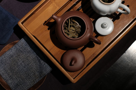 Tea set with teapot and cups on wooden tray.