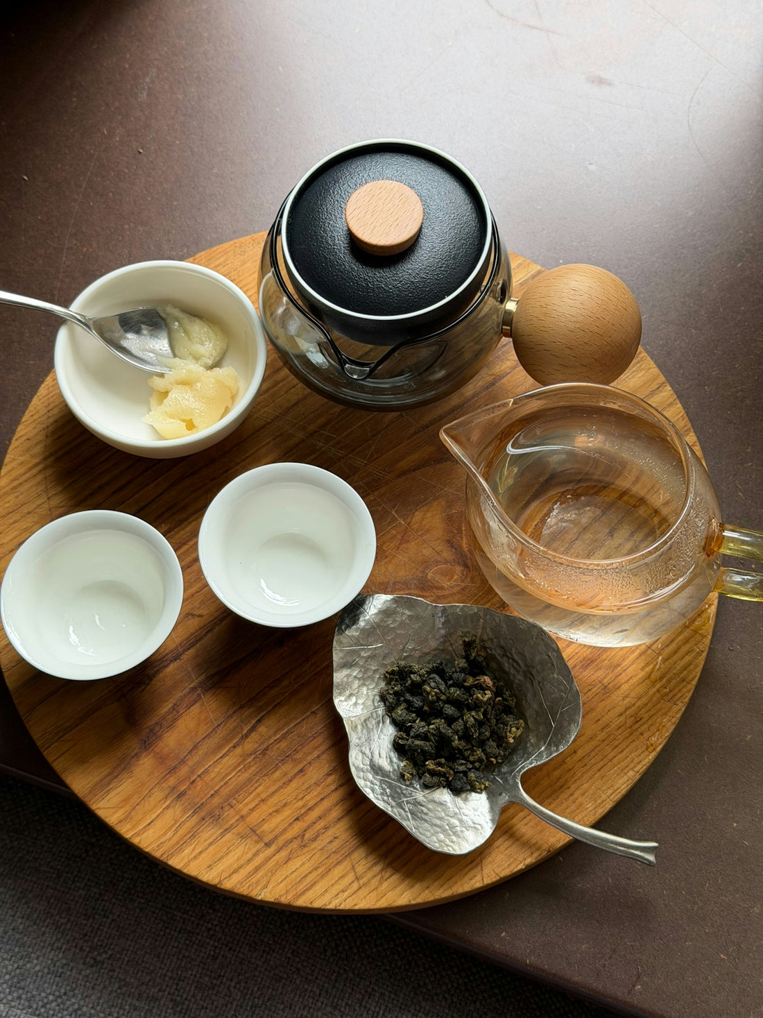 Tea leaves, cups, and teapot on a round wooden tray