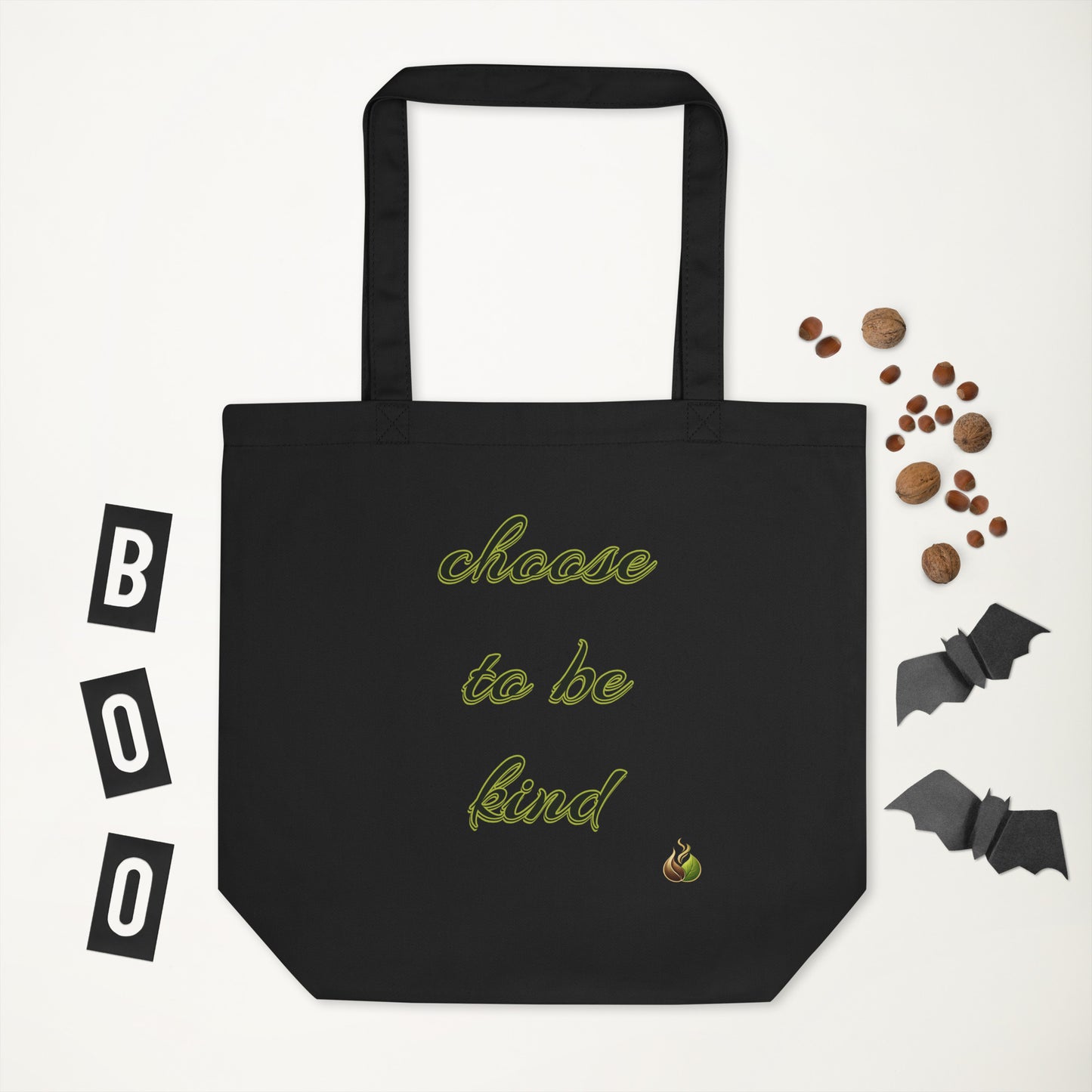 Black tote bag with a logo, surrounded by Halloween-themed items on a white background