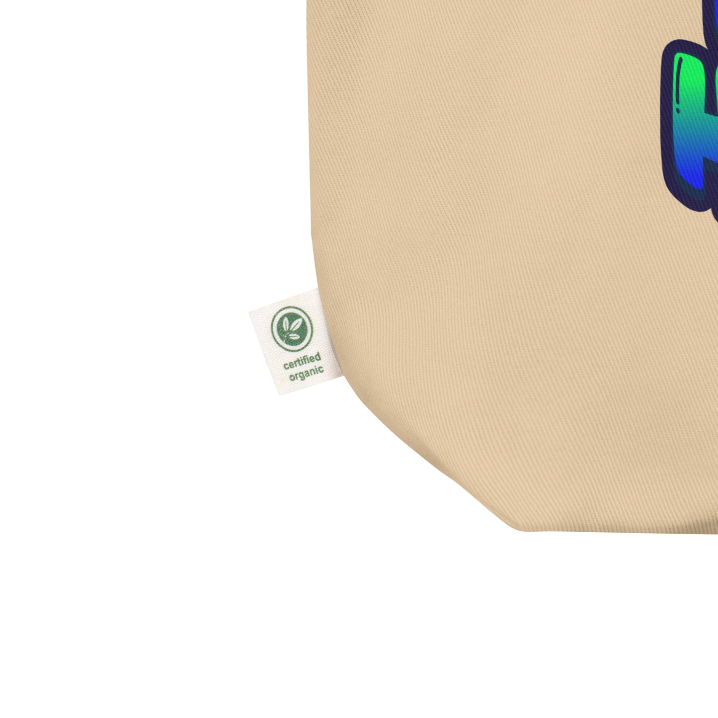 Close-up of a beige canvas tote bag corner with a green Certified Organic tag attached and part of a blue, green, and black graphic printed on the side, set against a plain white background.